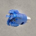 Angled view of blue PDC drill bit with polycrystalline diamond cutters and threaded connection.